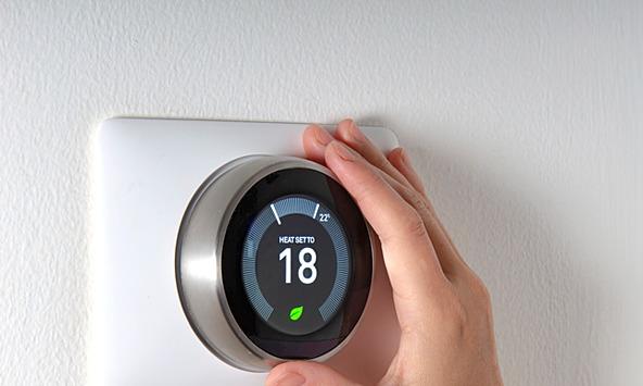 Hand adjusting a heating thermostat with temperature displayed as 18